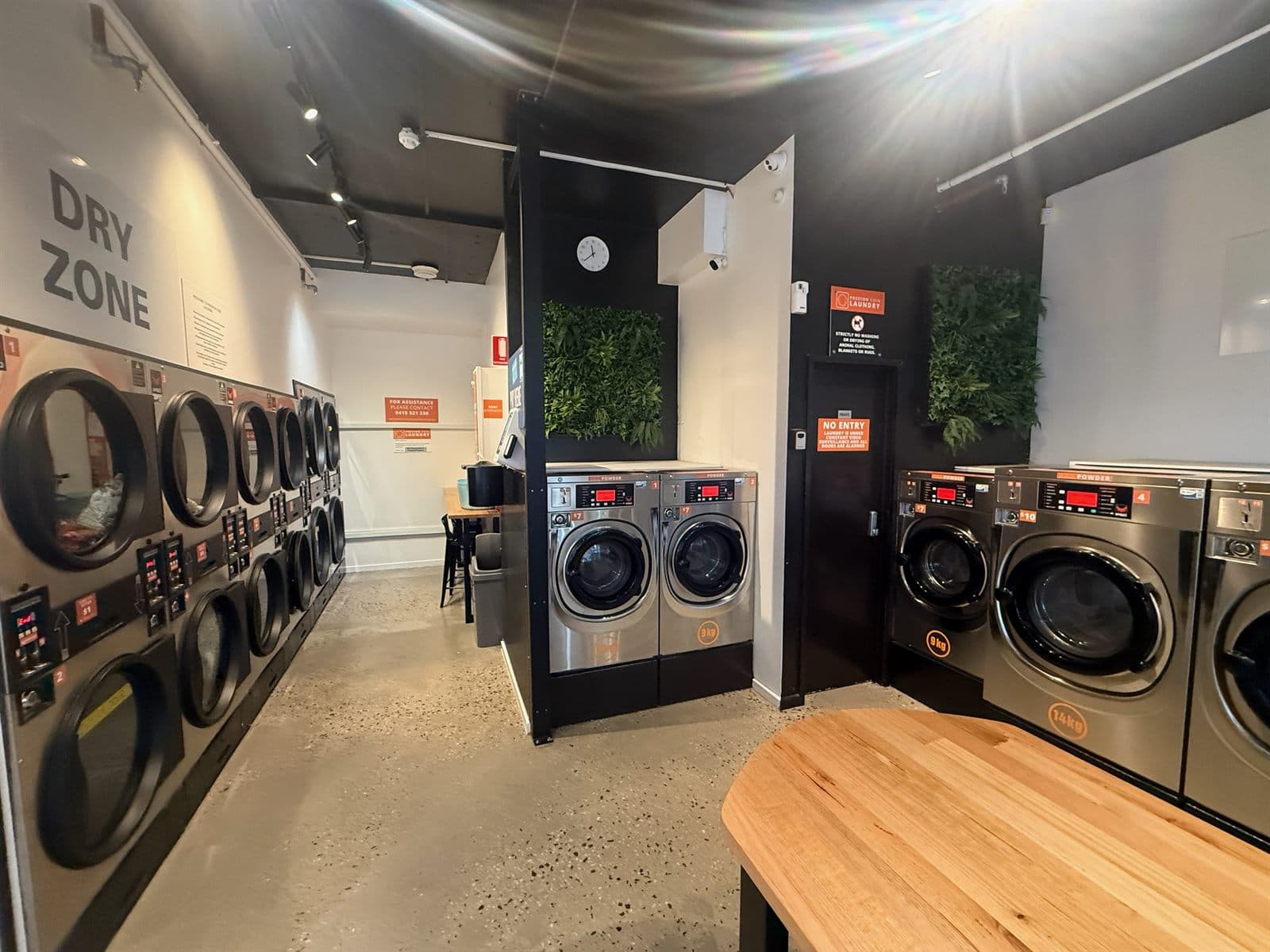 Bright, spacious interior at Preston Laundry House with rows of commercial washers, dryers and folding space